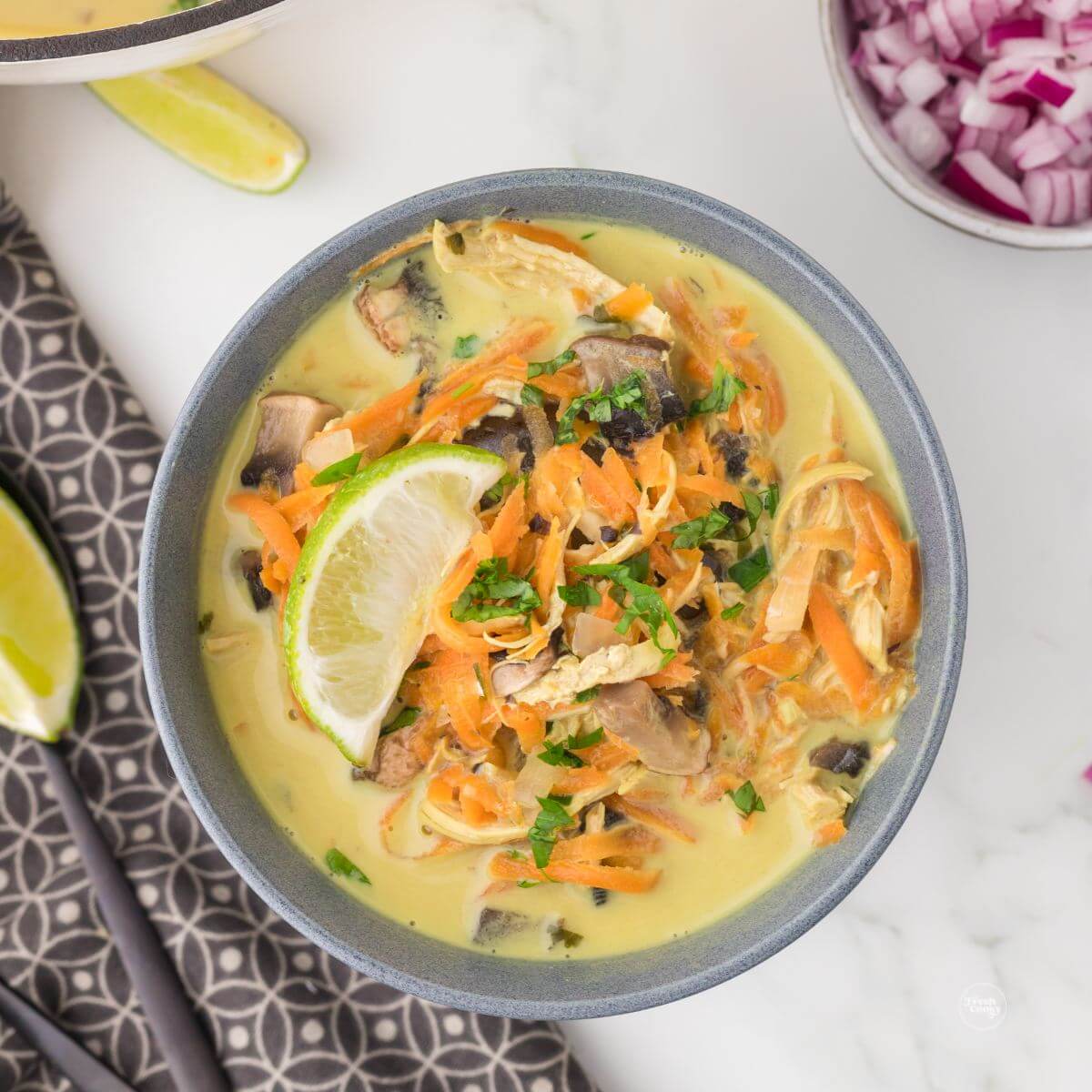 Panera Thai Chicken Soup in gray bowl garnished with lime wedge and cilantro. 