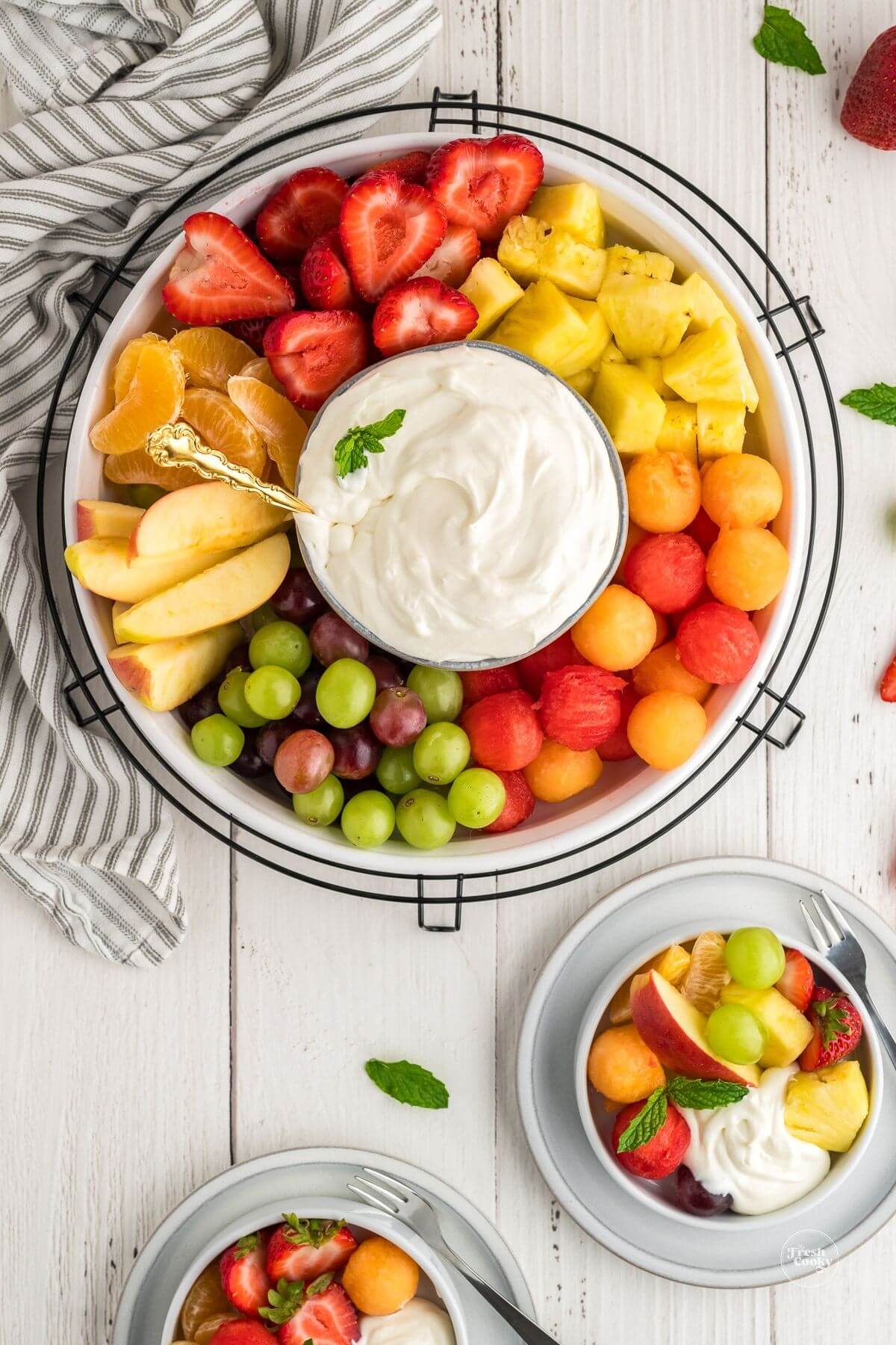 3 ingredient cream cheese fruit dip recipe, a couple of servings on appetizer plates surrounded by fruit.