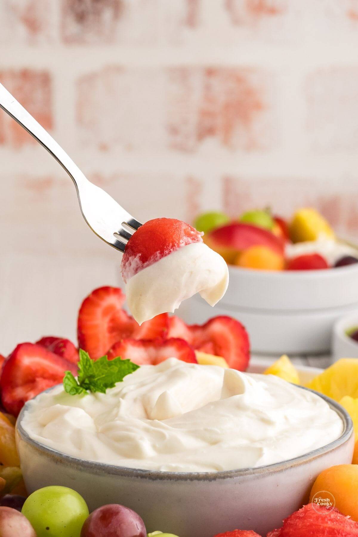 3 ingredient cream cheese fruit dip, with forked melon ball dipped into dip.