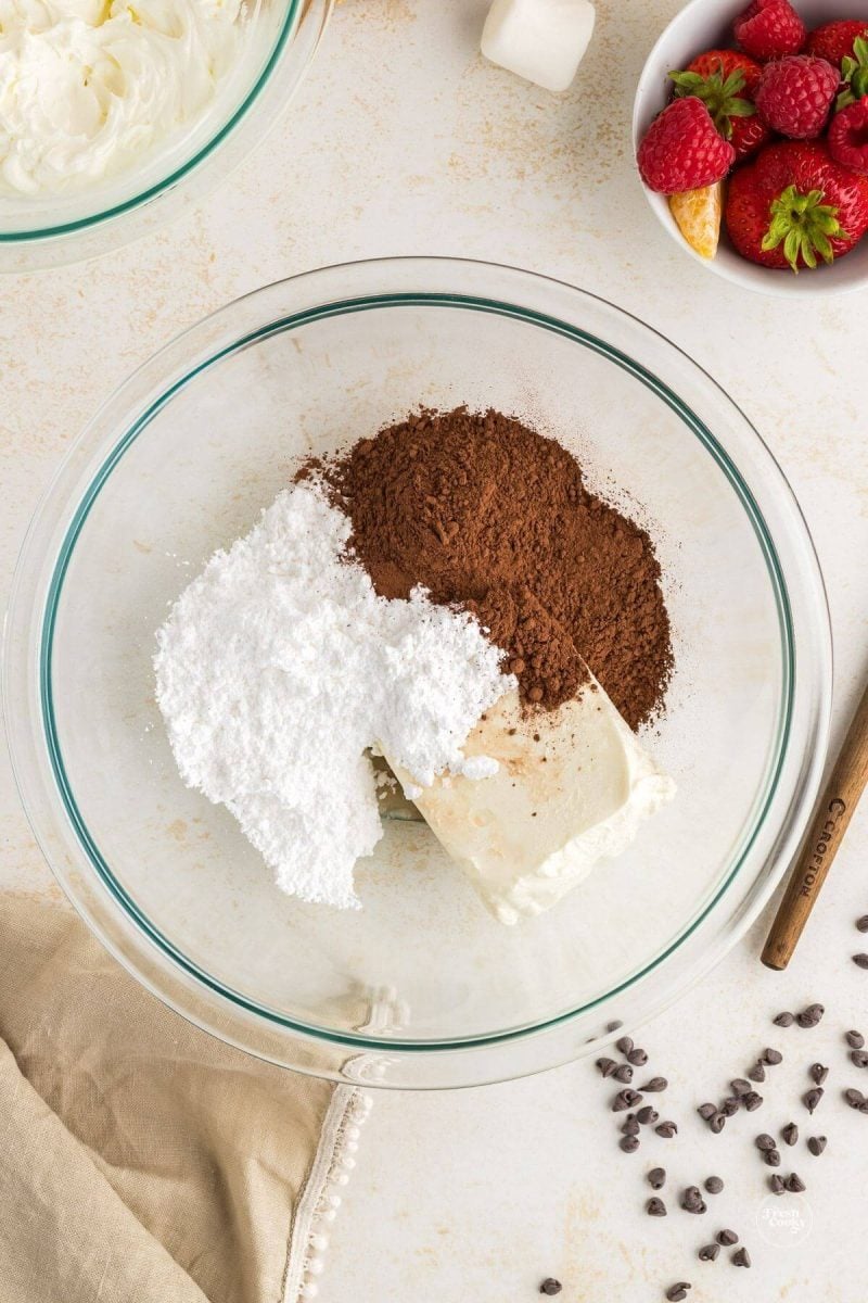 Cream cheese, cocoa powder and powdered sugar in bowl, ready to whip.