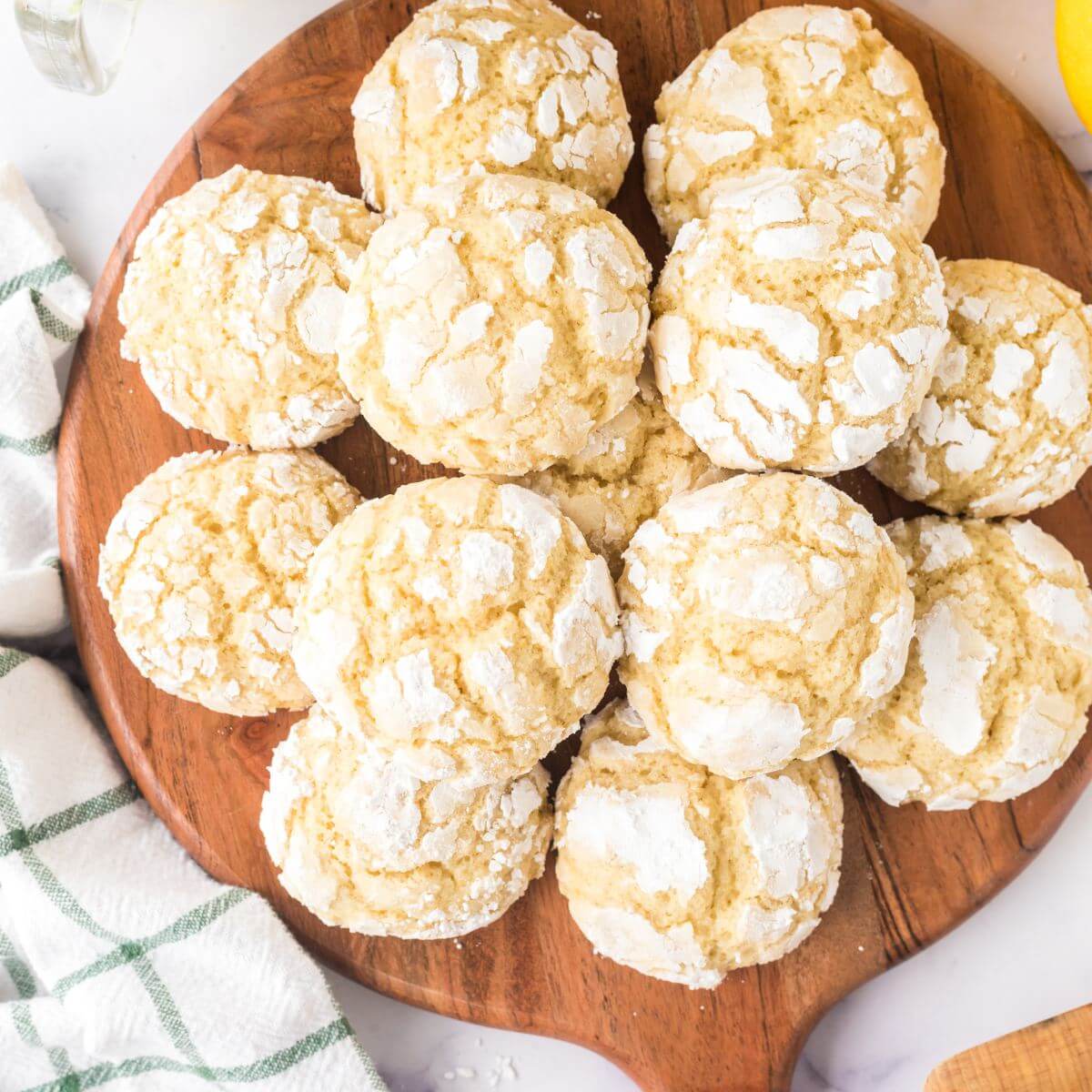 Lemon crinkle cookies on round cutting board.