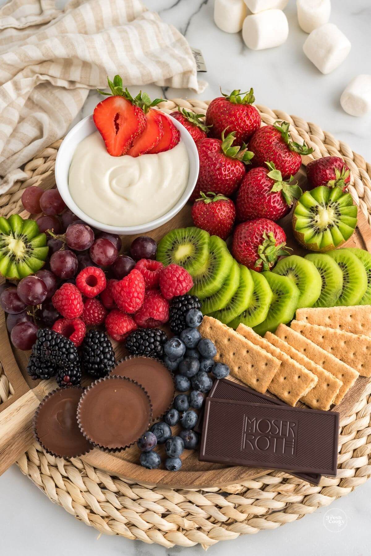 3 ingredient fruit dip with marshmallow fluff on tray with fresh fruit, chocolate and graham crackers.