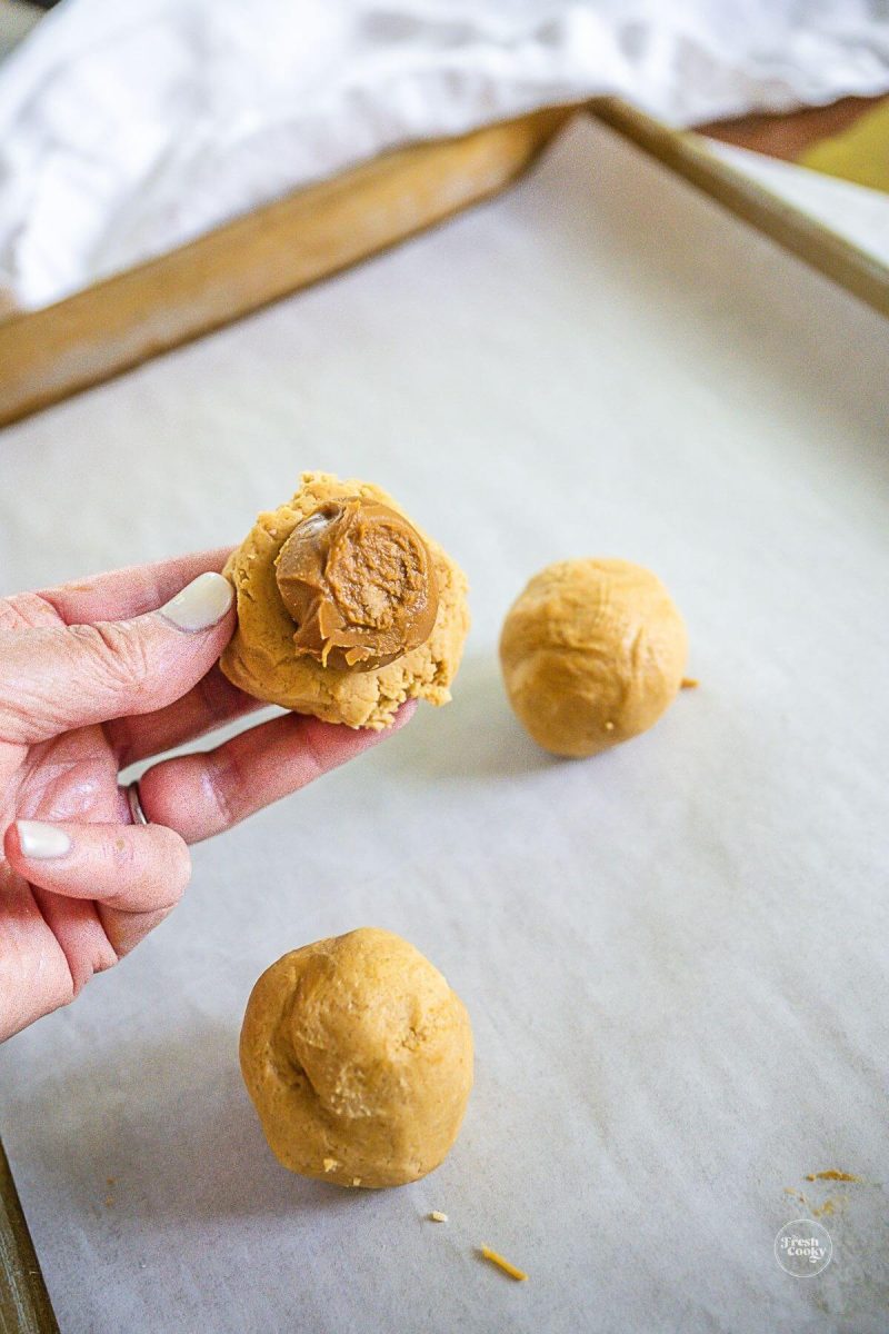 Place frozen cookie butter dollops in the middle of a cookie dough ball.