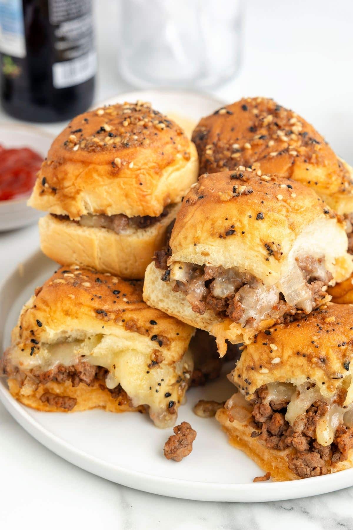 Cheeseburger Sliders stacked on plate with gooey cheese.