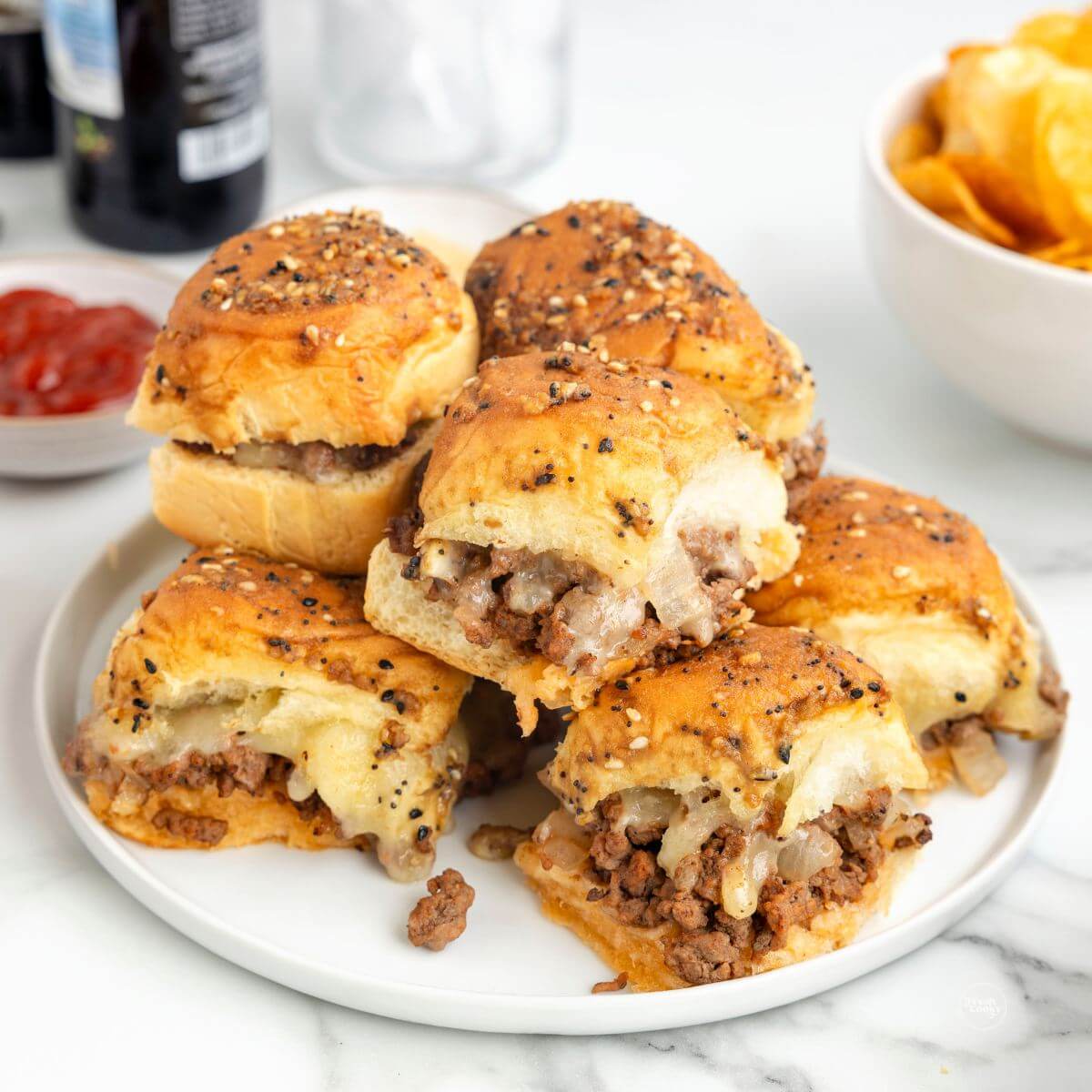 A plateful of cheeseburger sliders with Hawaiian rolls.