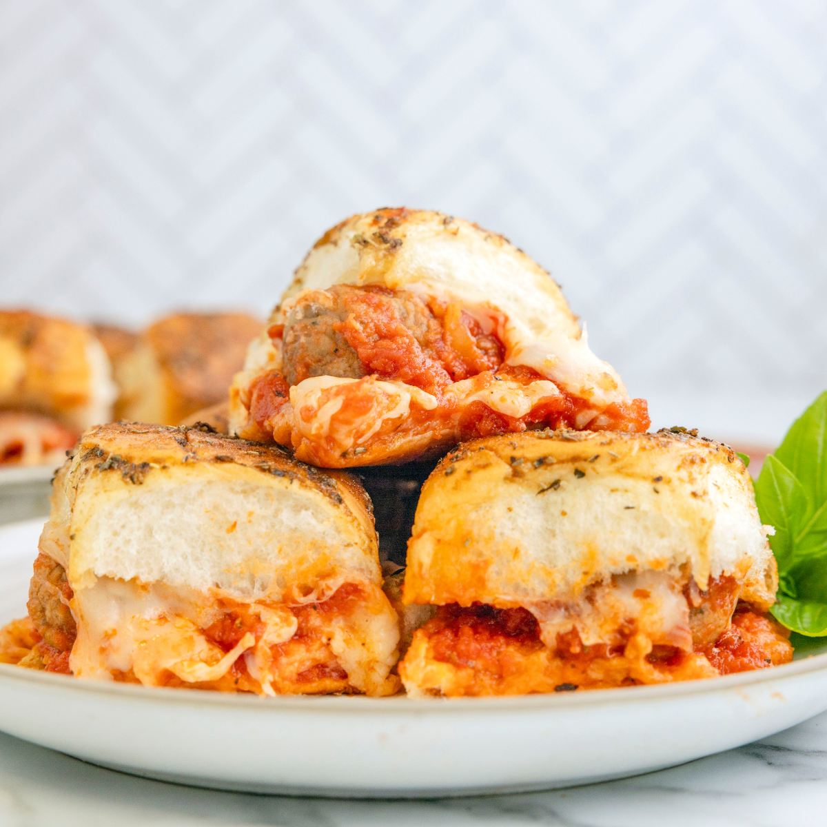 Easy meatball sliders on a plate ready to eat with gooey cheese.