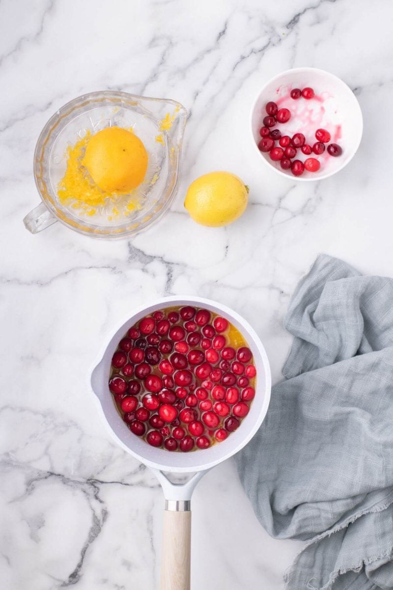 Add cranberries to simmering fruit juices. 