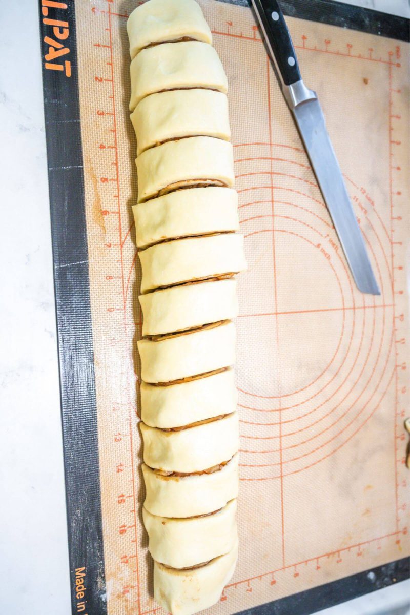 A long roll of cinnamon roll dough sliced into rolls.