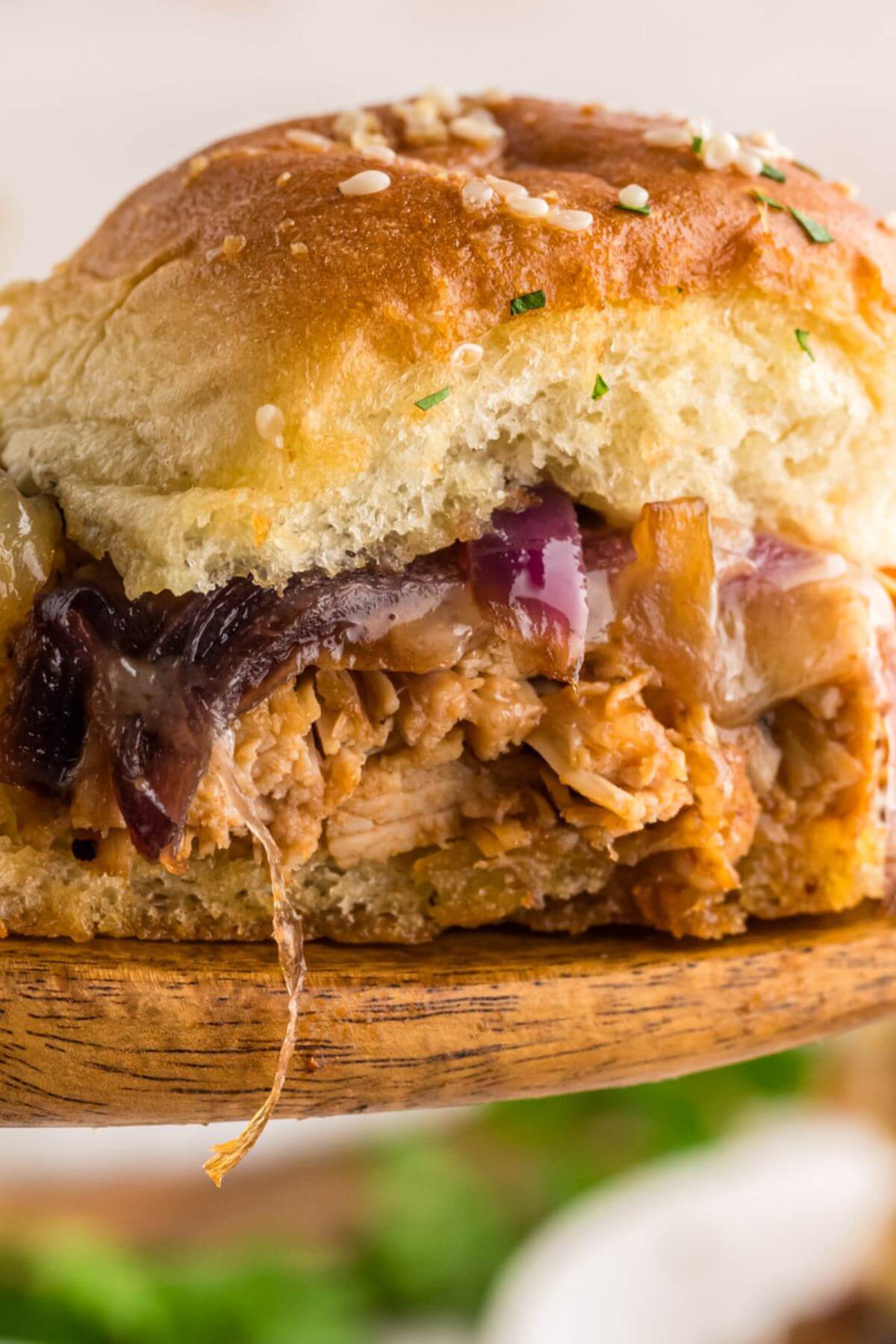 BBQ Chicken Slider lifted up on wooden spoon showing filling.