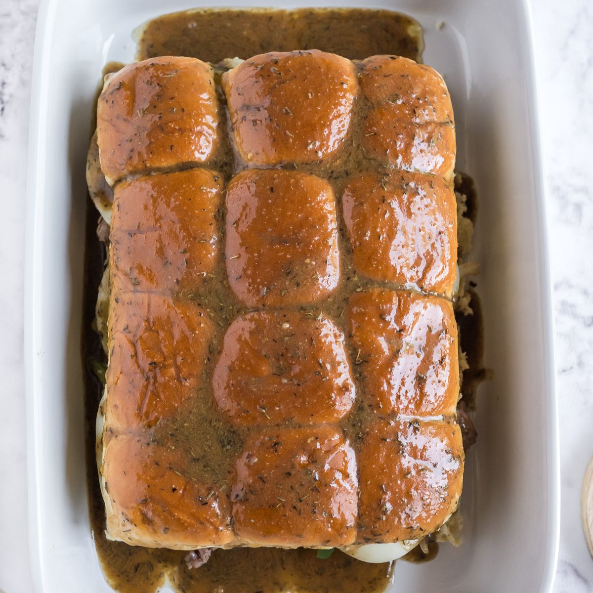 The butter sauce poured and basted over the tops of the Philly sliders.