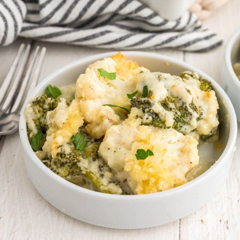 Bowl of cheesy Broccoli Cauliflower Casserole in a single bowl next to a fork and fine napkin.