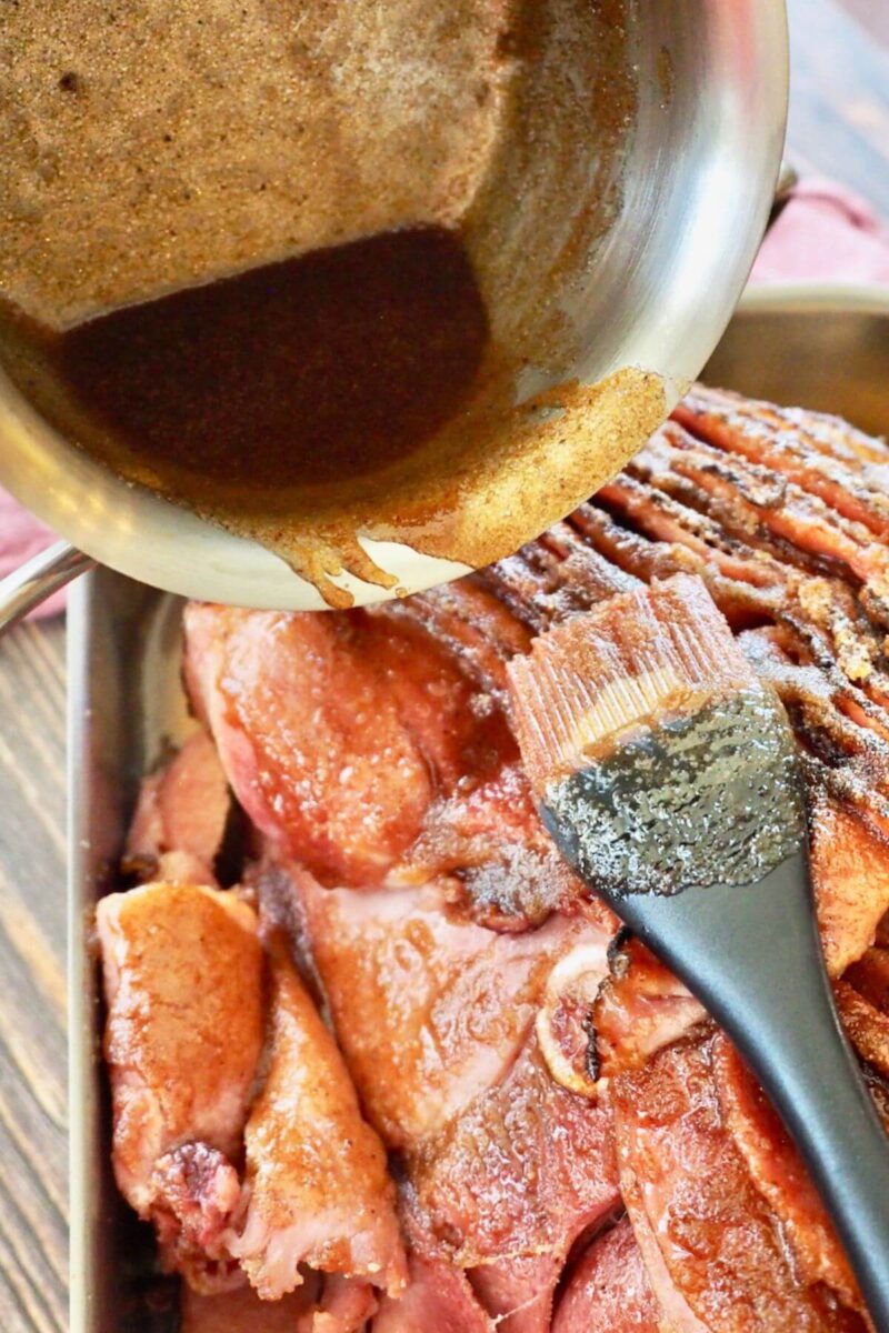 Pouring honeybaked ham sugar glaze over top of warmed ham for broiler.