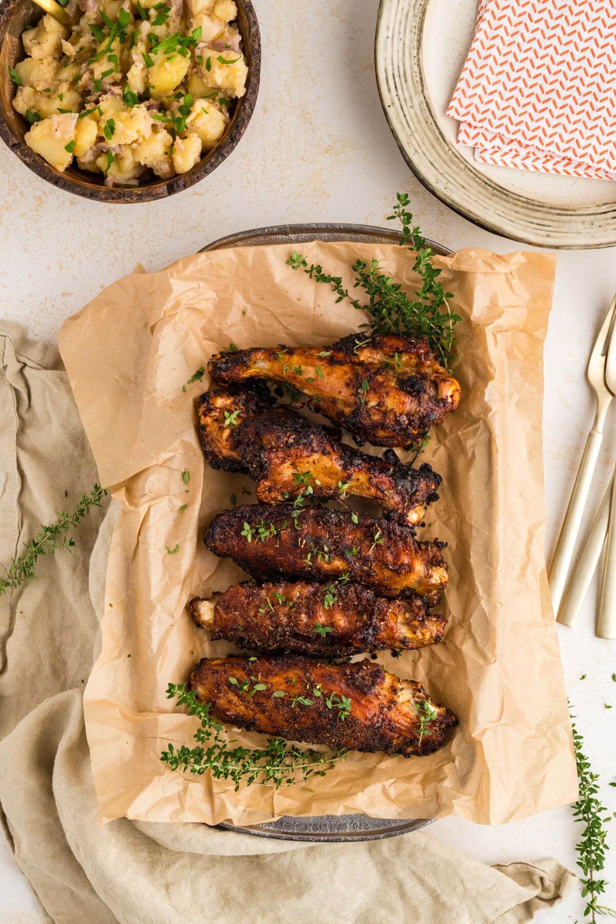 Crispy seasoned Turkey Wings Recipe laid in a row on pan near side dishes.