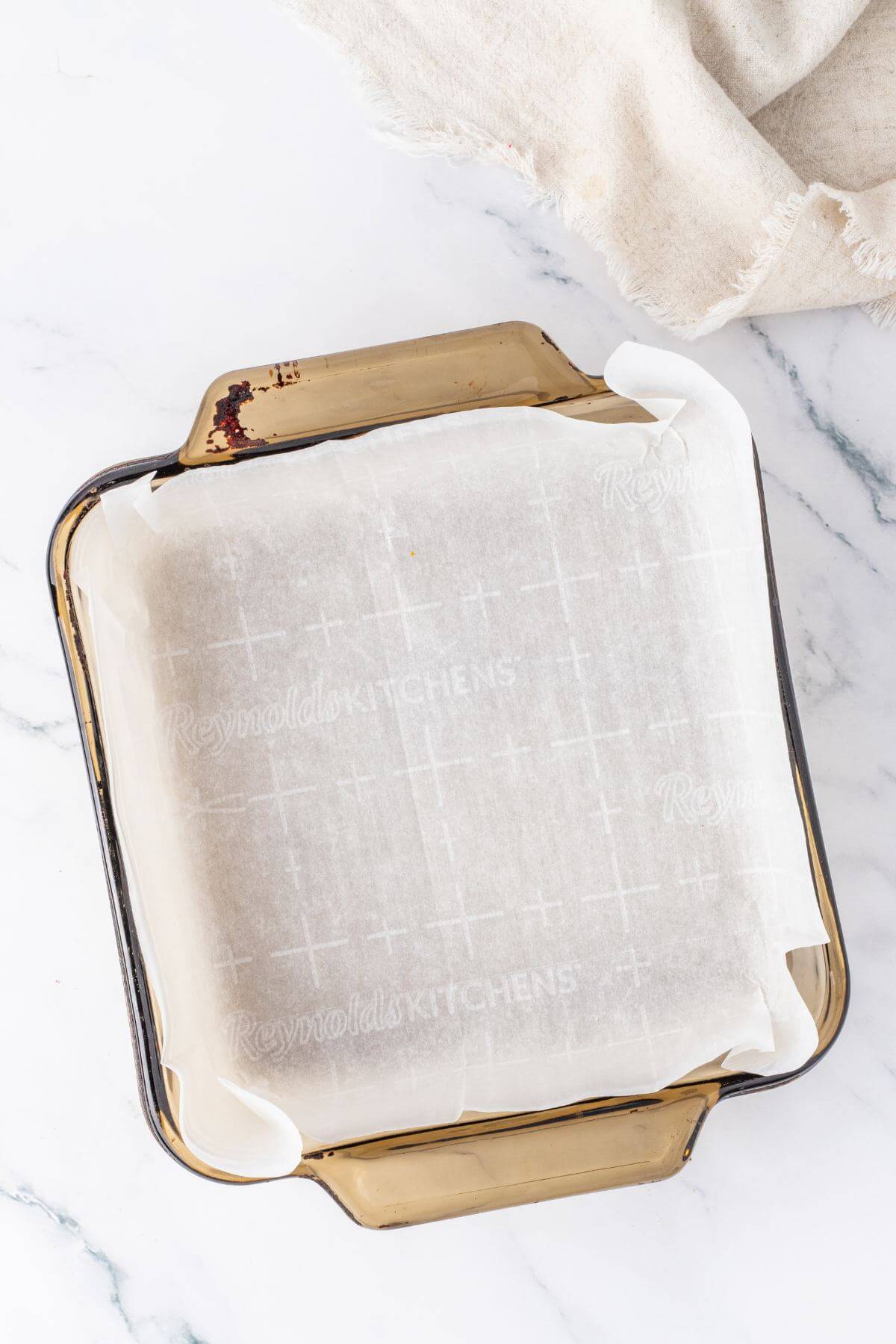 Square pan lined with parchment paper for hot chocolate fudge. 