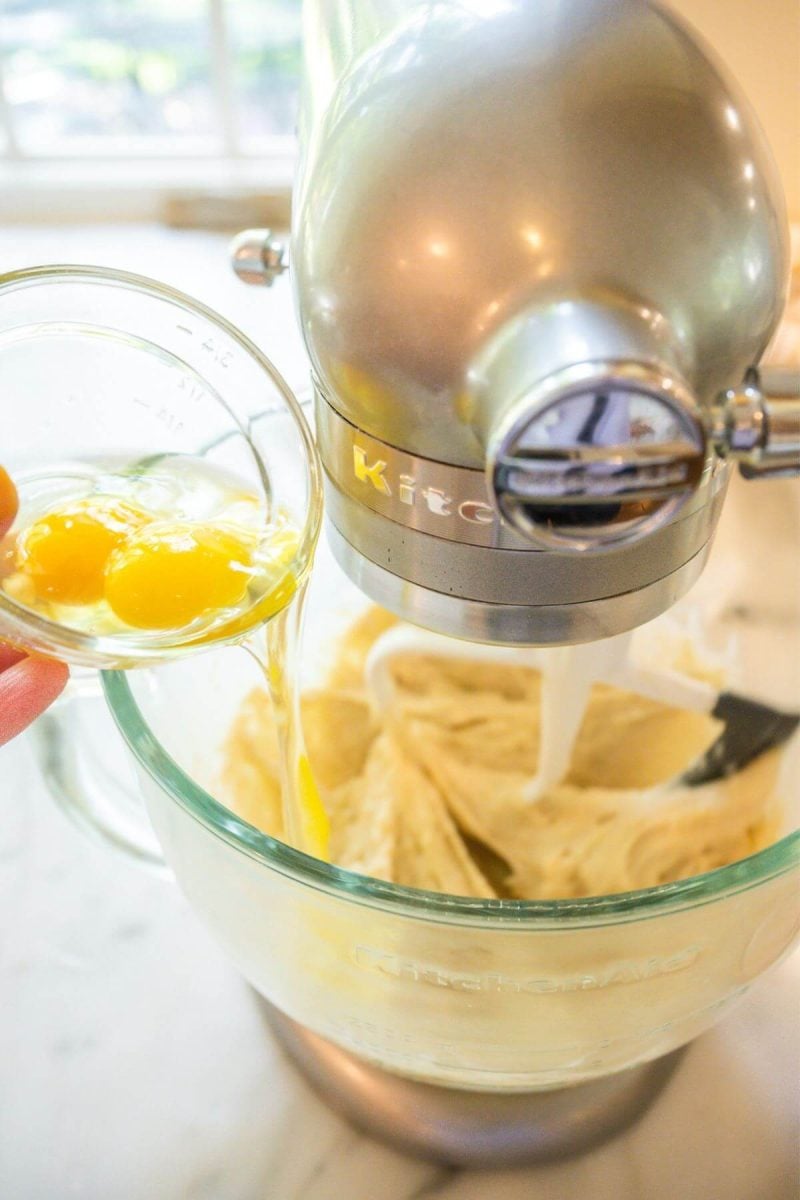 Adding eggs to cinnamon roll dough with paddle attachment. 