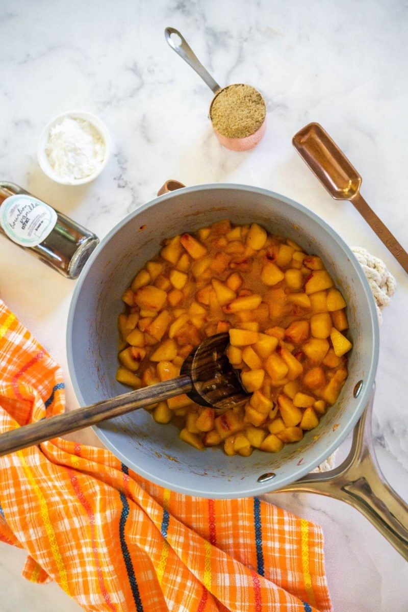 Adding water and chopped peaches to pan. 