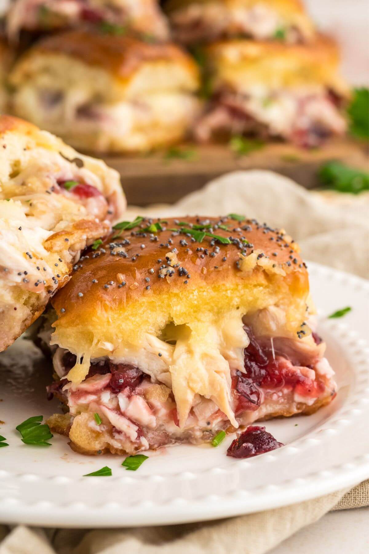 Close up of easy turkey sliders showing layers of turkey, cheese, cranberry sauce all on Hawaiian rolls.