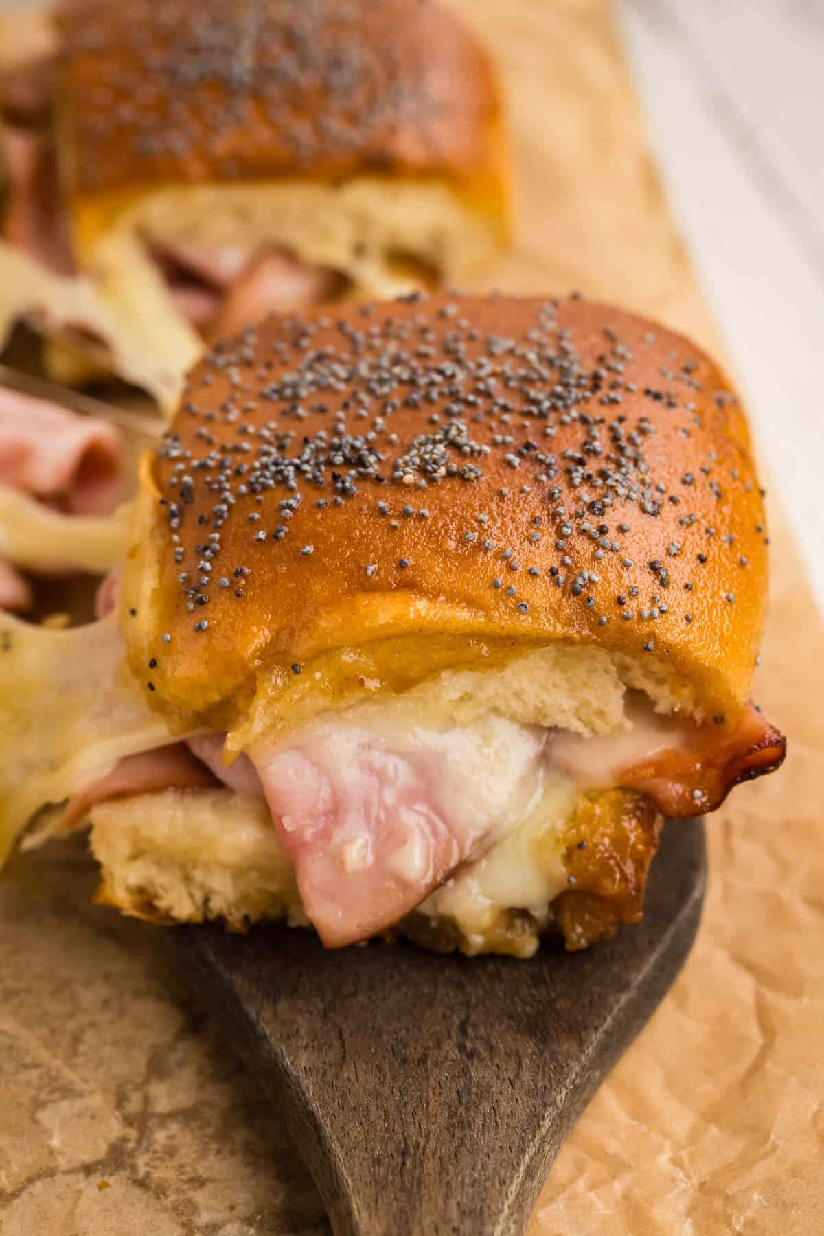 A close-up of a Hawaiian ham and cheese slider with gooey cheese. 