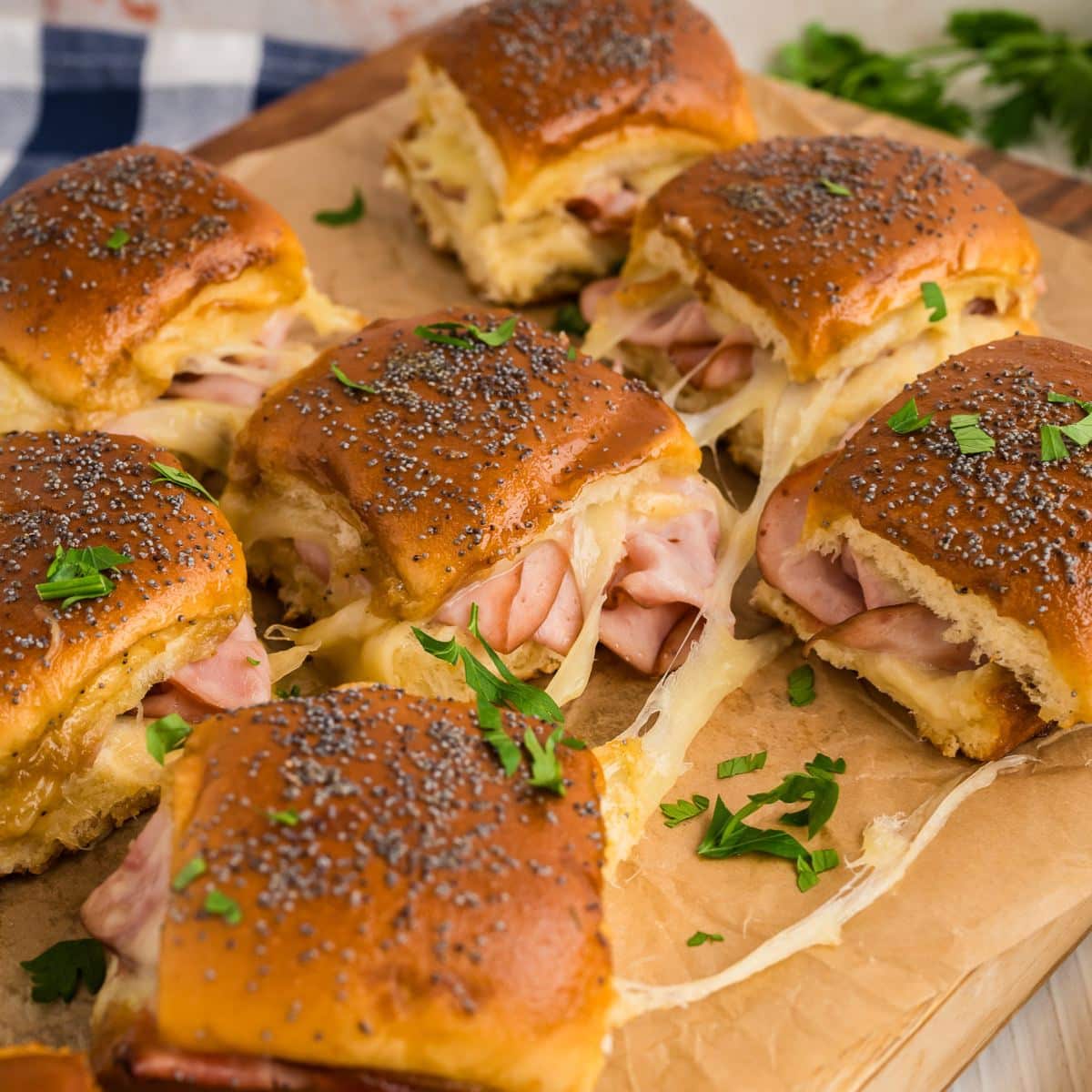 Gooey, cheesy, ham and swiss sliders ready for serving on a cutting board.