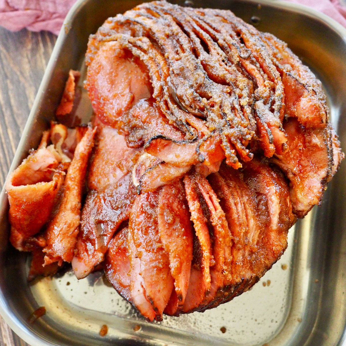 Spiral sliced ham with honey baked ham glaze in roasting pan.