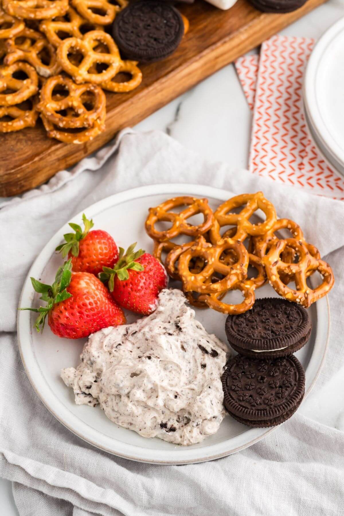 Serving of Oreo cookie dip with strawberries, extra Oreos and pretzels.