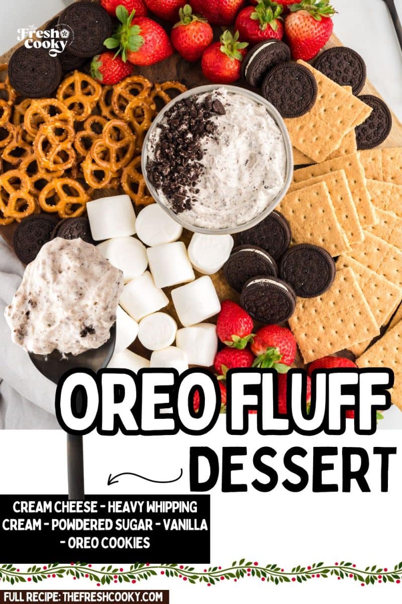 Easy Oreo fluff dessert in a bowl surrounded by fresh fruit, marshmallows, Oreo cookies and graham crackers, to pin.