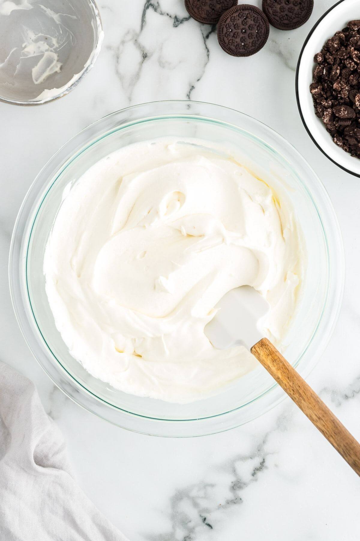 Whipped heavy cream in a large bowl with spatula.