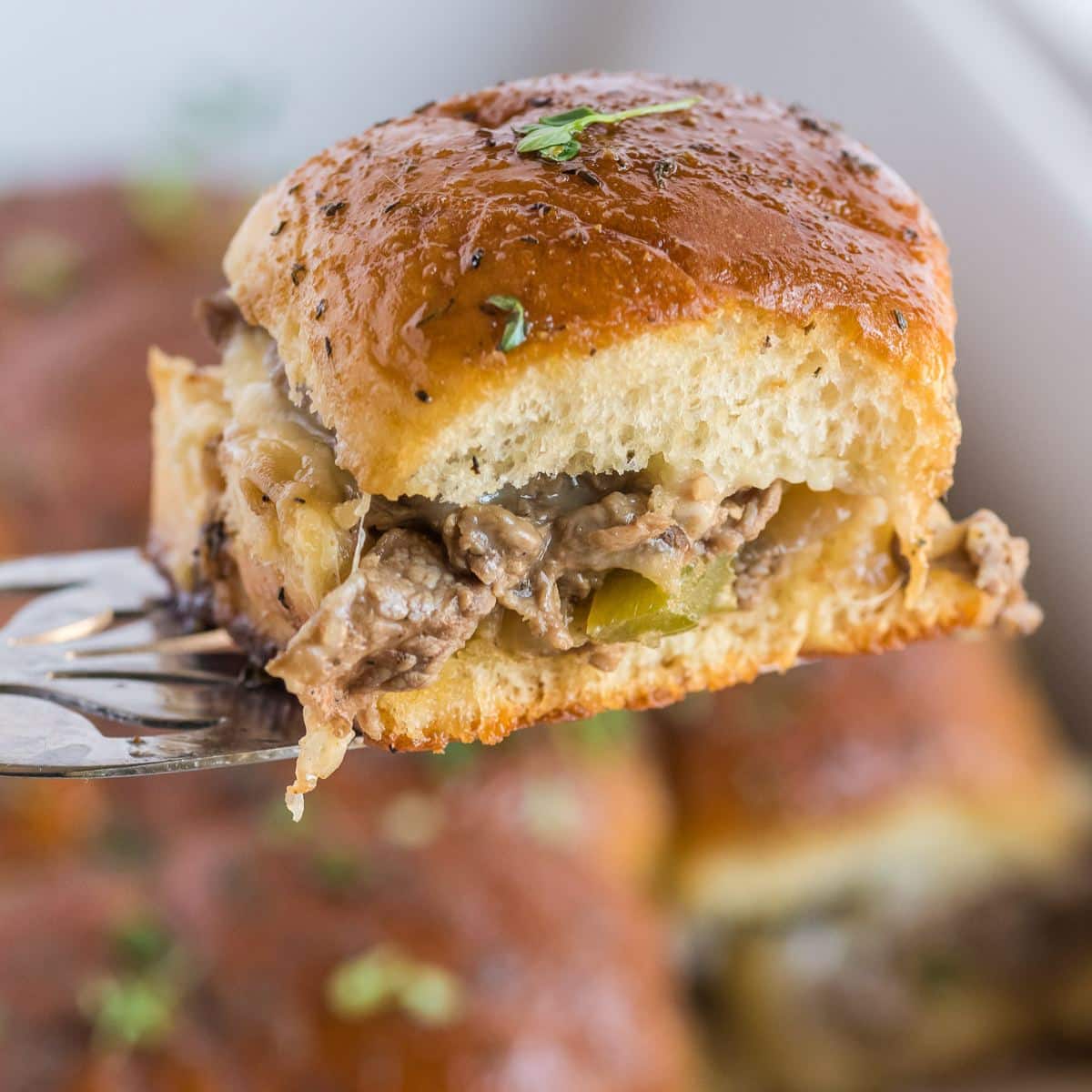 Philly Cheese steak sliders on a spatula for serving.