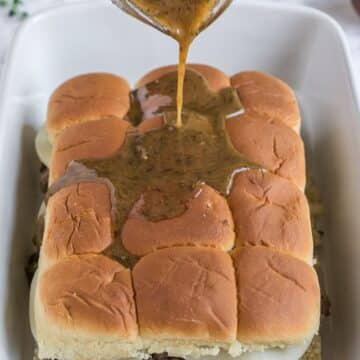 Pouring the butter mixture over the tops of the sliders.