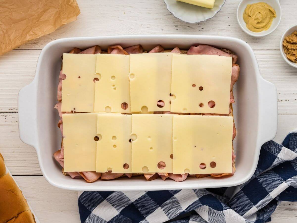 Swiss cheese added to the tops of the ham sliders.
