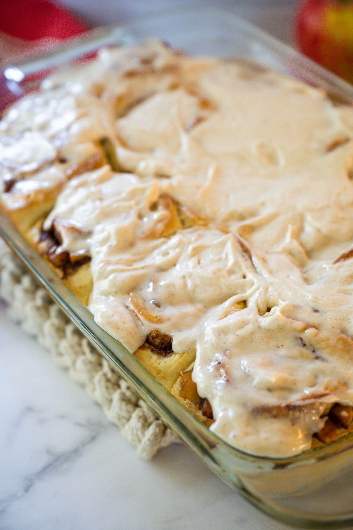 Pan of iced cinnamon rolls with apple pie filling.