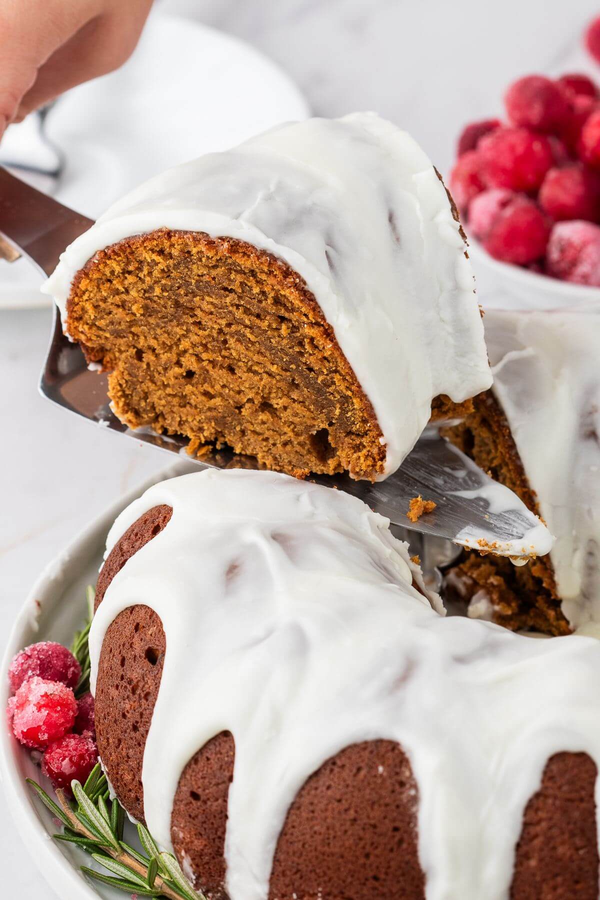 Serving a slice of moist and yummy Gingerbread bundt cake iced with a white glaze.