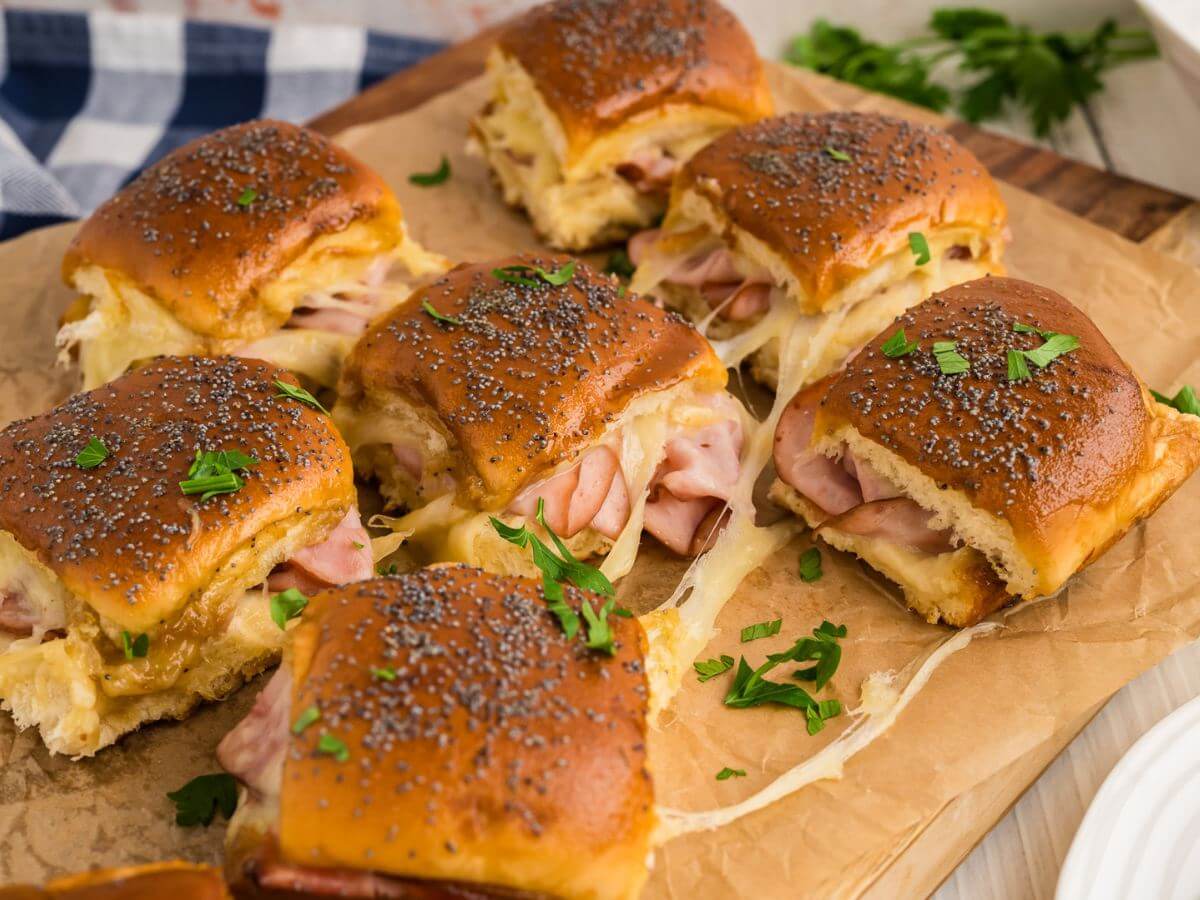 Ham and cheese sliders served on a wooden board.