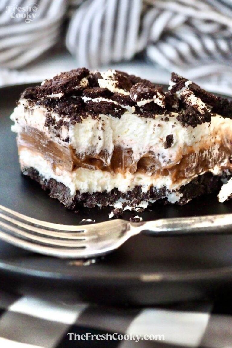 A slice of oreo delight on a black plate with a fork.