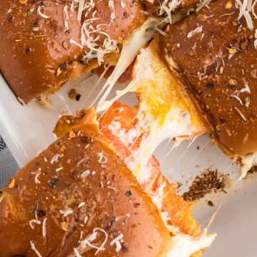 Square image of a close up view of a pizza slider sandwich pulling away from the