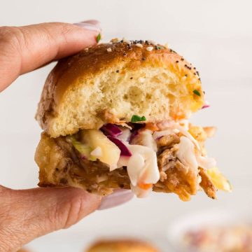 Someone holding one of the pulled pork sliders on hawaiian rolls.