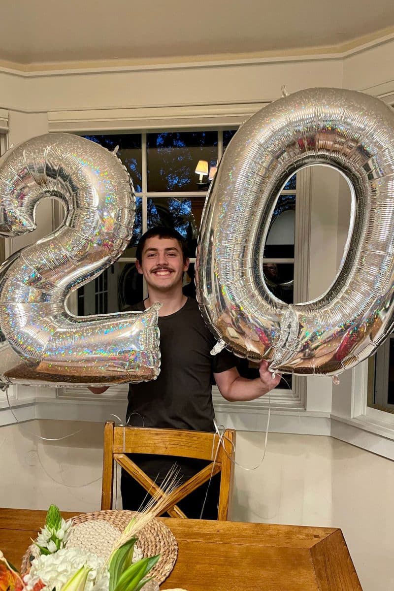Our 20 year old son holding 2 & 0 balloons. 