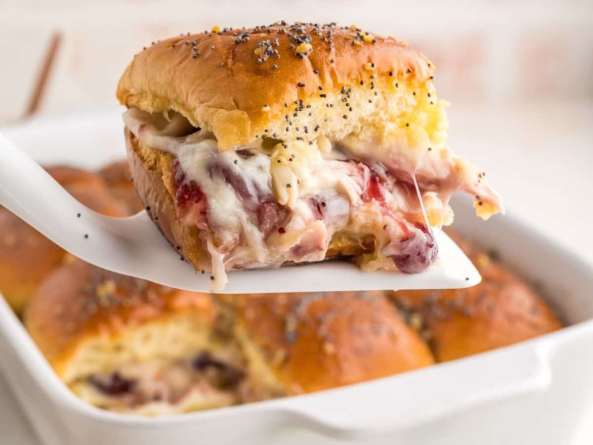 Turkey and cheese sliders with cranberry on a spatula, for serving.