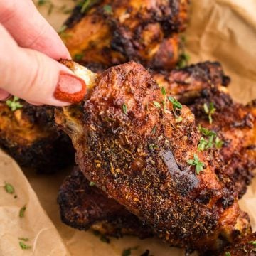 someone lifting turkey wings in air fryer from pan.