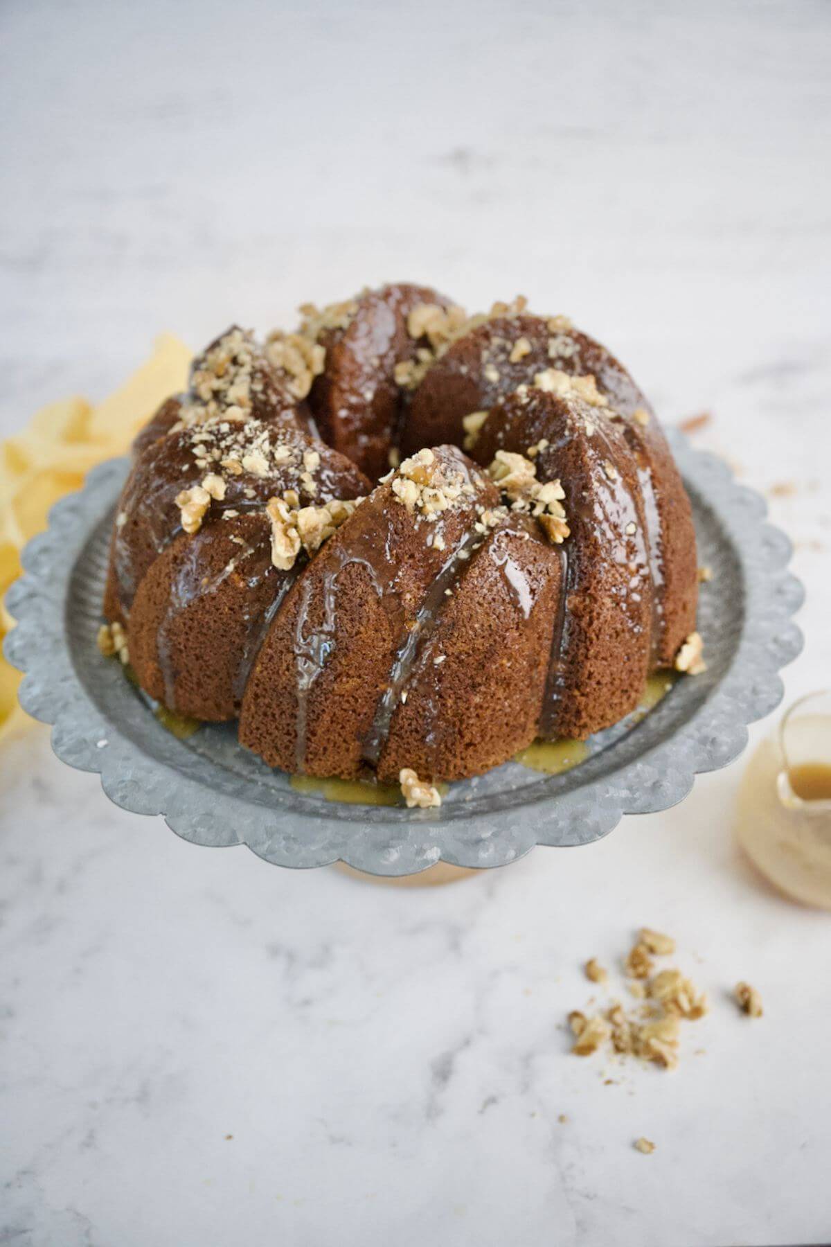 Banana Bread Bundt Cake served on platter topped with walnuts.
