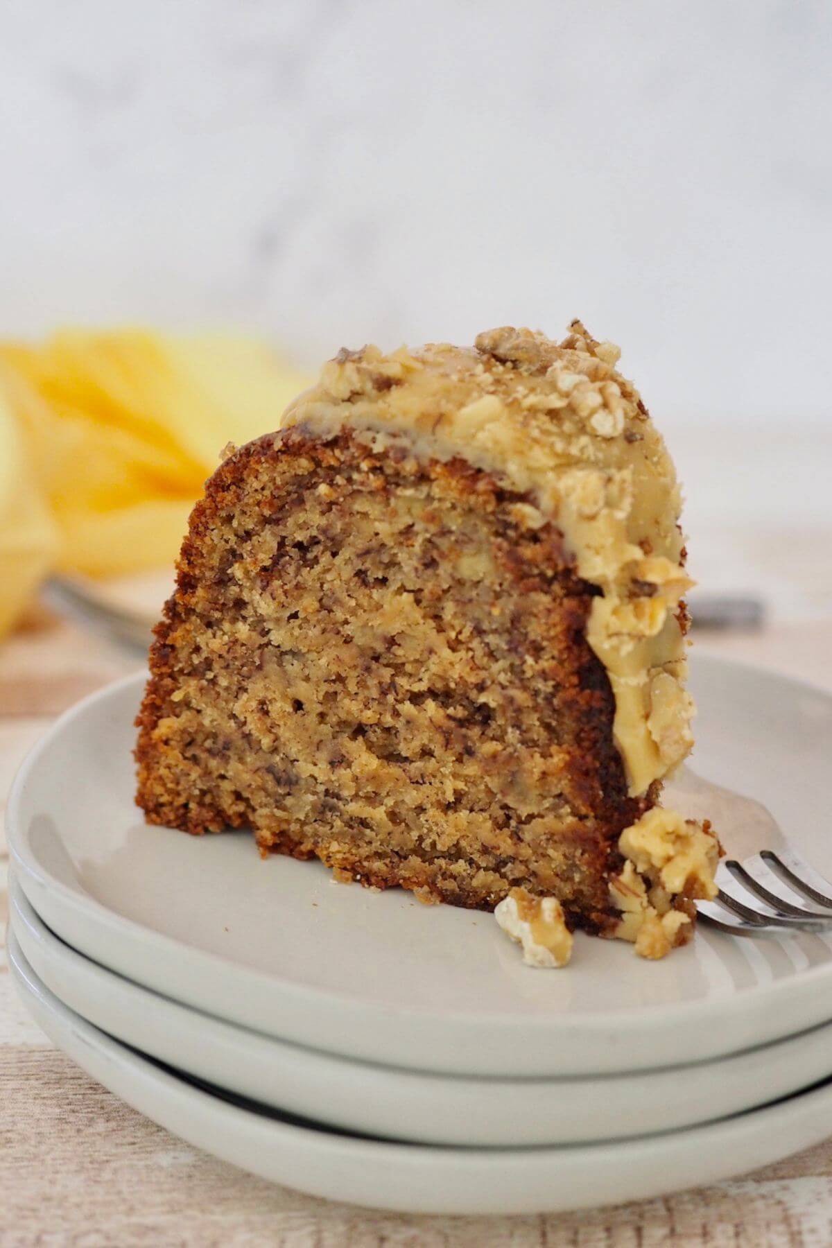Slice of best Banana Bread Bundt Cake with sauce and walnuts on plate.