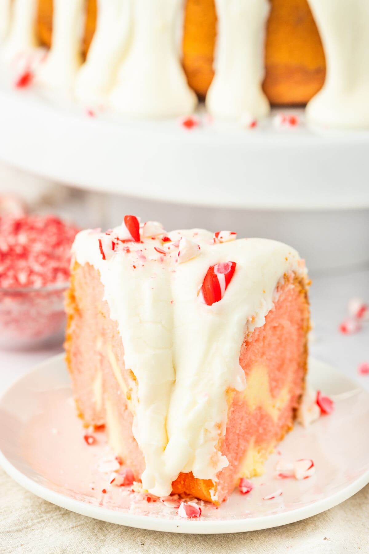 Slice of Christmas Peppermint Bundt Cake served on plate by peppermints.