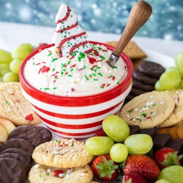 Red striped bowl filled with Little Debbie Christmas tree dip surrounded by cookies, fruit and other dippers.