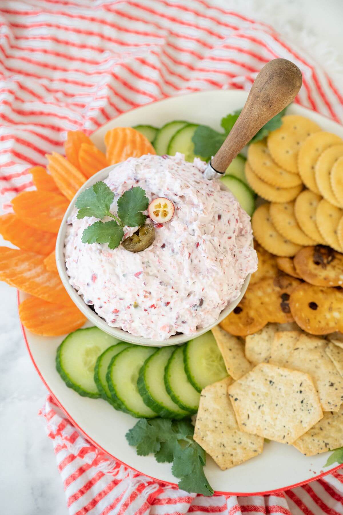 Top view of bowl of dip surrounded by carrots, cucumbers, and crackers.