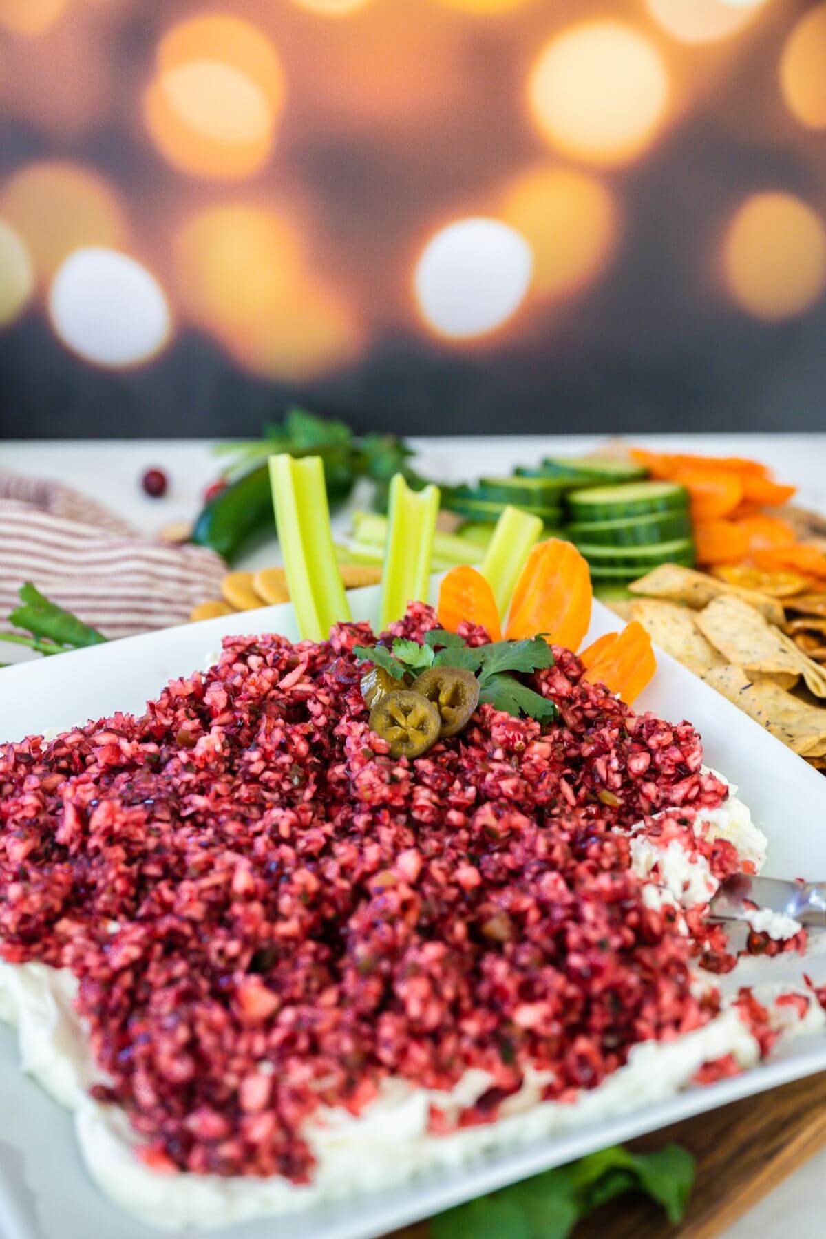 Cranberry Jalapeno Dip is served in dish with celery and other vegetables.