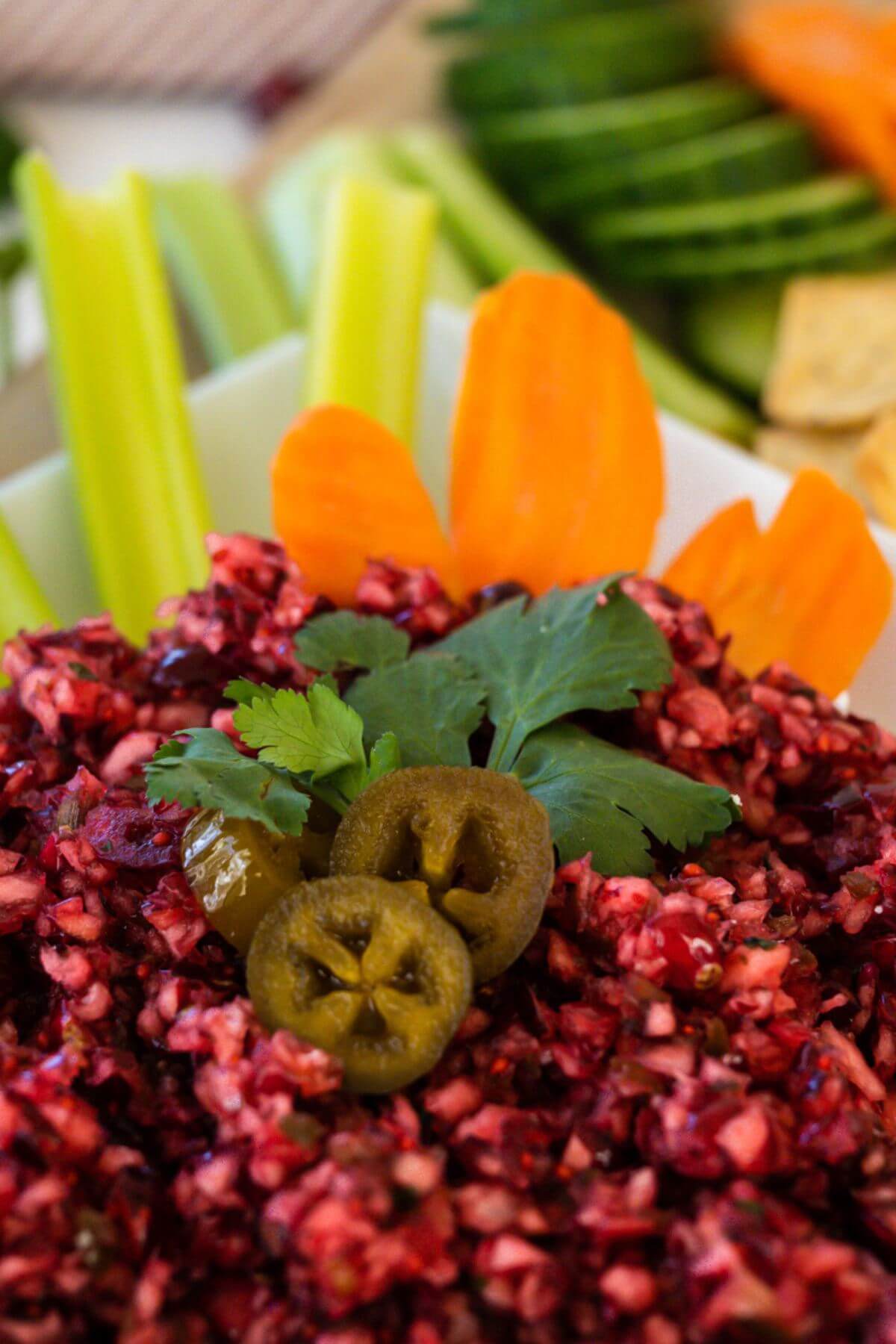 Cranberry dip is garnished with jalapenos alongside vegetables.