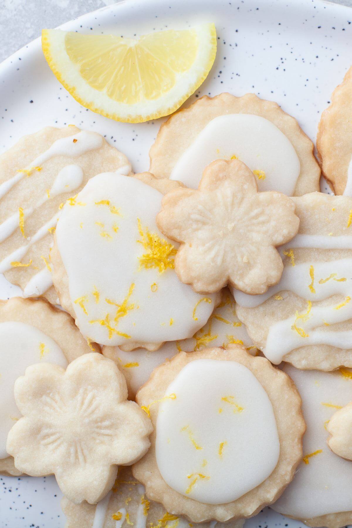 Lemon cookies shaped into flowers and round cookies are iced.