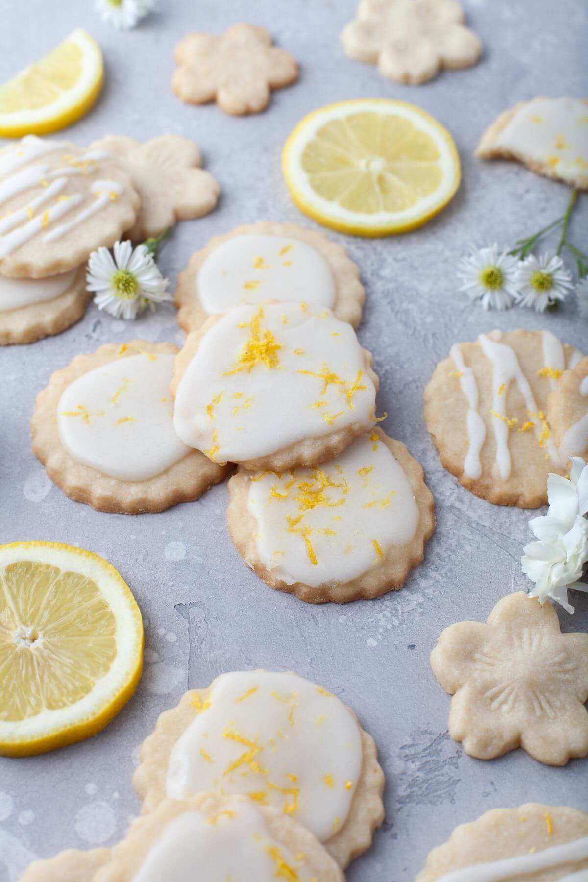 Iced cookies in different shapes are displayed with flowers and lemons.