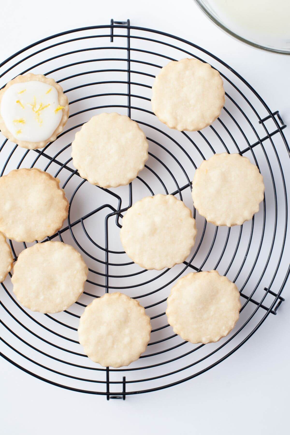 Cookies shown on wire rack, one cookie is iced.