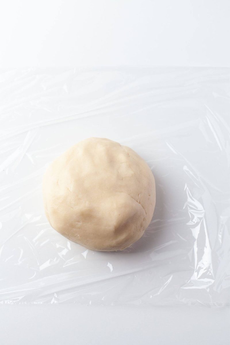 A disc of cookie dough lays on plastic wrap.
